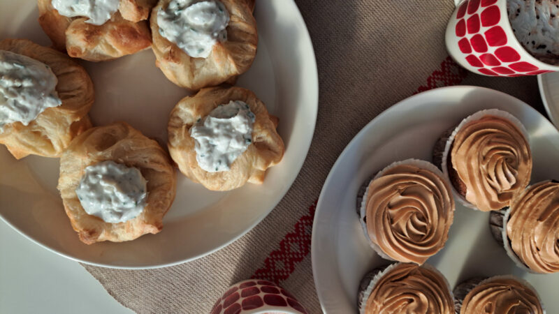 Lautasille aseteltuna suolaisia torttuja ja kuorrutettuja muffinseja.