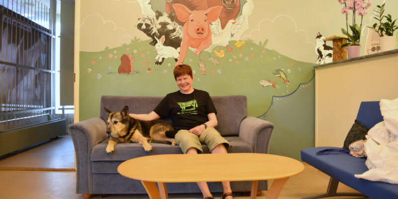 Erja Saarto istuu sohvalla Tessu-koiran kanssa.