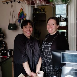 Elli ja Sofia Uuksulainen seisovat Rakastan-kahvilan tiskin takana.