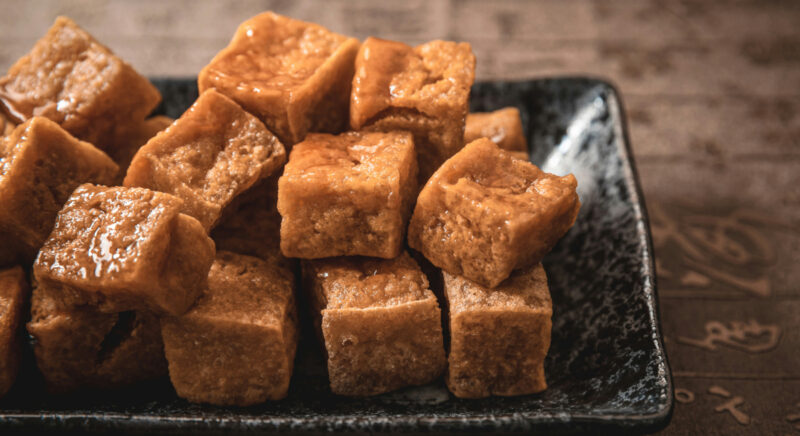 Pilkottua tofua mustalla lautasella.